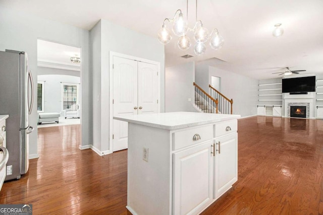 kitchen featuring stainless steel refrigerator, white cabinets, pendant lighting, and dark hardwood / wood-style floors