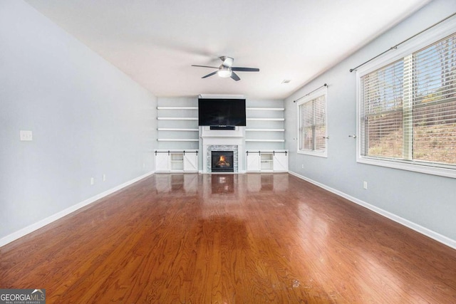 unfurnished living room with a fireplace, hardwood / wood-style floors, ceiling fan, and built in shelves