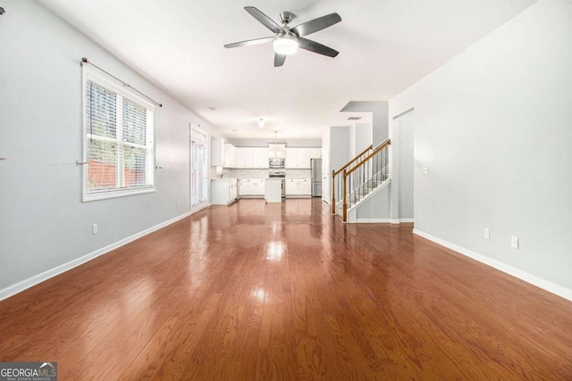 unfurnished living room with ceiling fan and wood-type flooring