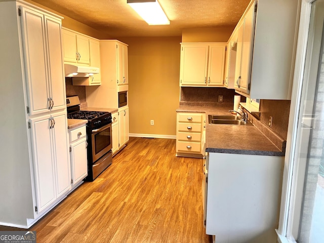 kitchen with built in microwave, white cabinetry, sink, light hardwood / wood-style flooring, and stainless steel range with gas cooktop