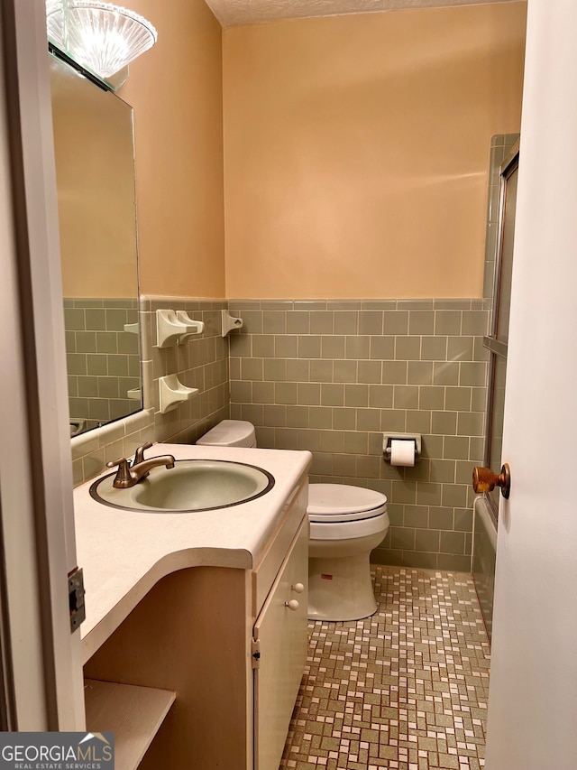 bathroom featuring vanity, toilet, tile walls, and tile patterned floors