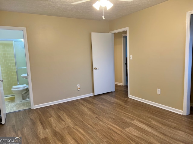 unfurnished bedroom featuring hardwood / wood-style floors, a textured ceiling, connected bathroom, and ceiling fan