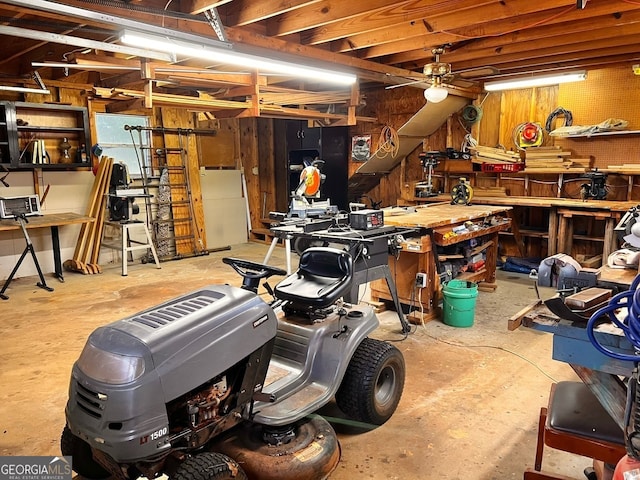 interior space featuring ceiling fan, a workshop area, and wooden walls