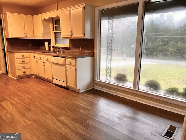 kitchen featuring white dishwasher, sink, backsplash, white cabinetry, and light wood-type flooring