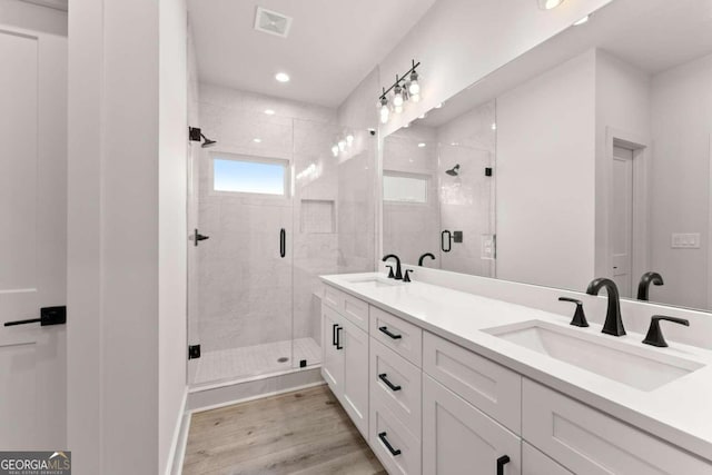 bathroom with hardwood / wood-style flooring, an enclosed shower, and vanity