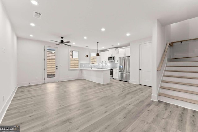 unfurnished living room featuring ceiling fan and light hardwood / wood-style flooring