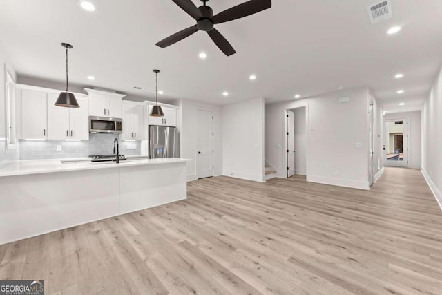 kitchen featuring decorative light fixtures, sink, white cabinets, decorative backsplash, and stainless steel appliances