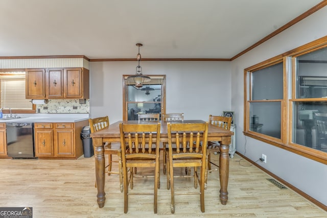 dining space with sink, light wood-type flooring, and ornamental molding