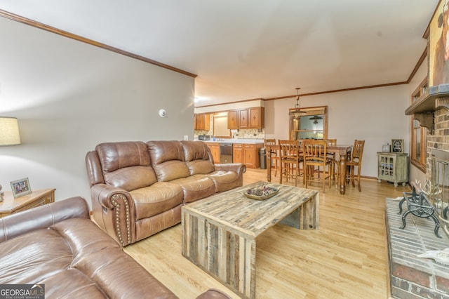 living room with a brick fireplace, crown molding, and light hardwood / wood-style flooring