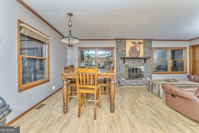 dining room featuring a fireplace, light hardwood / wood-style floors, and crown molding