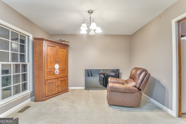 living area featuring light carpet and an inviting chandelier