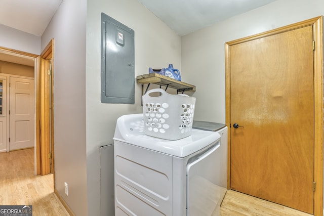 clothes washing area featuring electric panel, washer and dryer, and light hardwood / wood-style floors