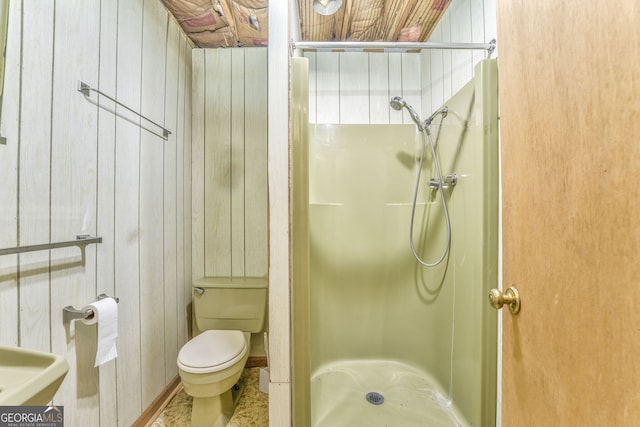 bathroom featuring toilet, wood walls, and a shower