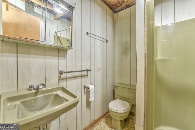 bathroom with wood walls, sink, and toilet