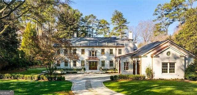 view of front of property with a front yard, driveway, and a chimney