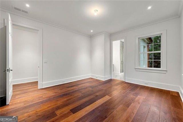 empty room featuring baseboards, ornamental molding, visible vents, and wood finished floors