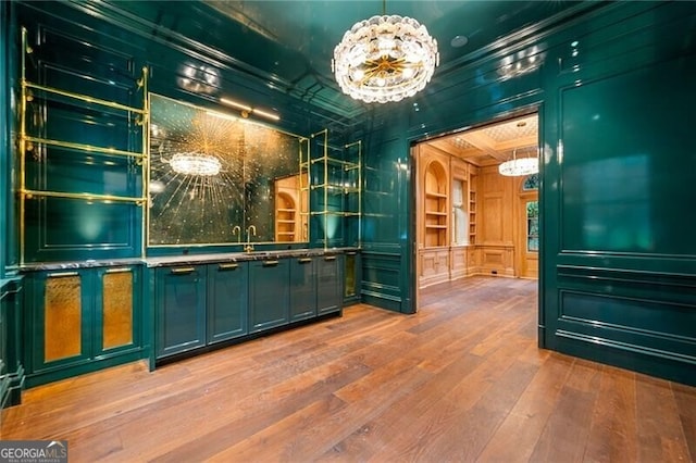 bar featuring a notable chandelier, coffered ceiling, crown molding, and wood finished floors