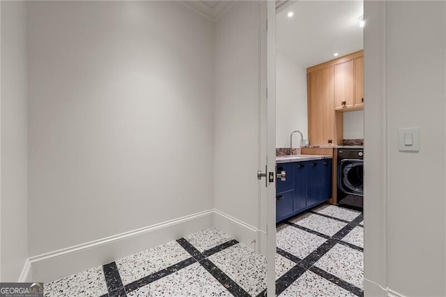 laundry room featuring baseboards, cabinet space, a sink, and washer / clothes dryer