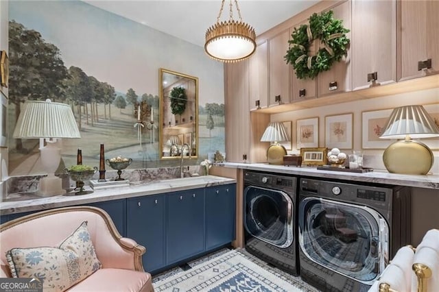 washroom with a sink, cabinet space, and washer and clothes dryer