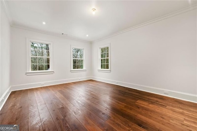 unfurnished room featuring baseboards, wood finished floors, plenty of natural light, and ornamental molding