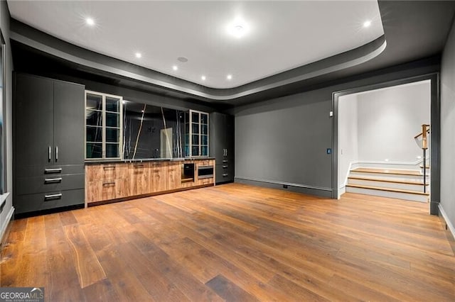 cinema room featuring a raised ceiling, wood finished floors, and recessed lighting