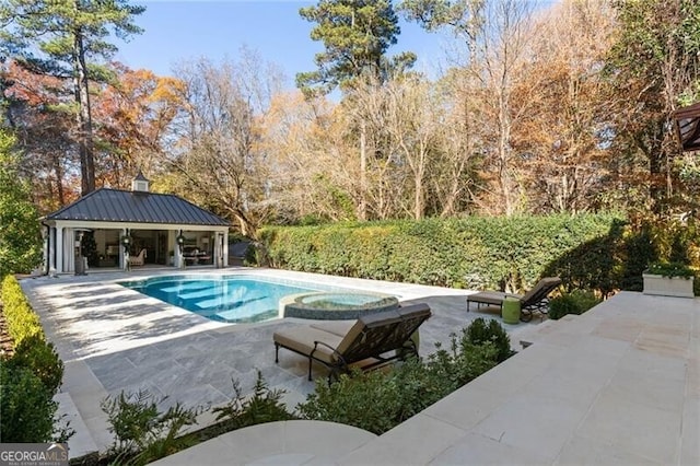 view of swimming pool featuring a pool with connected hot tub, an outbuilding, and a patio area