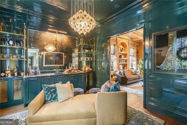 bar with ornamental molding, wet bar, a notable chandelier, wood walls, and wood finished floors