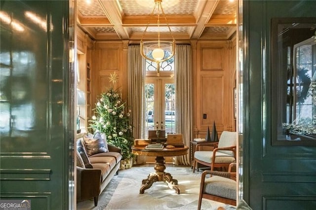 living area featuring beam ceiling, coffered ceiling, crown molding, wood walls, and french doors