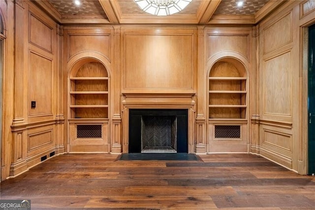 unfurnished living room with dark wood-type flooring, built in features, a fireplace with flush hearth, and crown molding