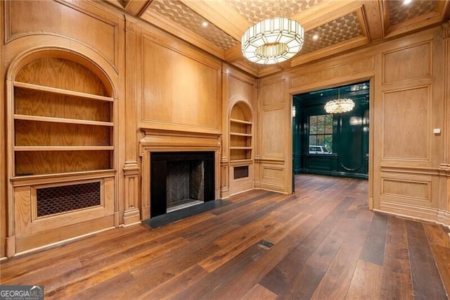 unfurnished living room with built in shelves, ornamental molding, a fireplace with flush hearth, and a decorative wall