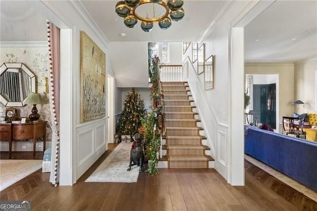 entrance foyer featuring stairway, ornamental molding, parquet flooring, and a decorative wall