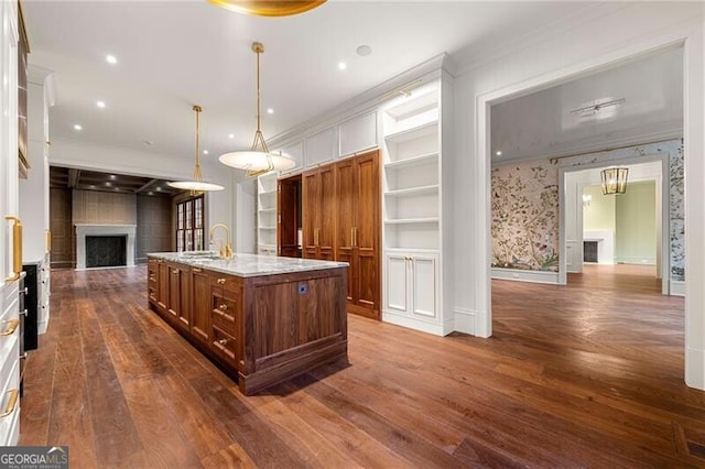 kitchen featuring ornamental molding, a fireplace, open floor plan, and an island with sink