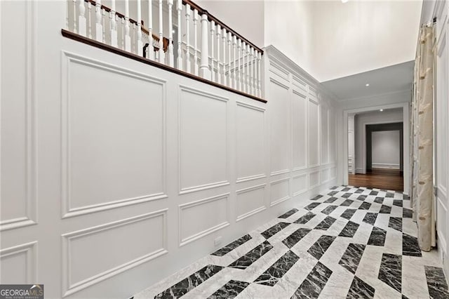 hall featuring marble finish floor, a high ceiling, and a decorative wall