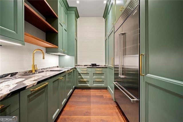 kitchen featuring a sink, stainless steel built in fridge, and green cabinets