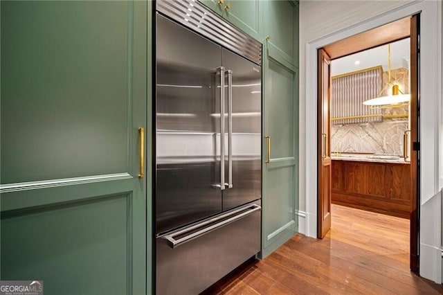 kitchen featuring green cabinetry, stainless steel built in fridge, and wood finished floors