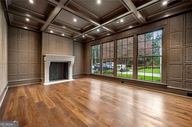 unfurnished living room with a fireplace, a decorative wall, wood finished floors, and coffered ceiling