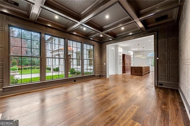 spare room featuring coffered ceiling, wood finished floors, and beamed ceiling