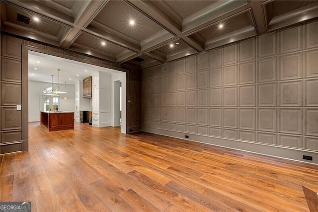 unfurnished living room featuring light wood finished floors, coffered ceiling, recessed lighting, and beam ceiling