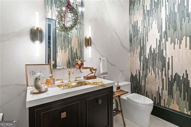 bathroom with vanity, tile walls, and toilet