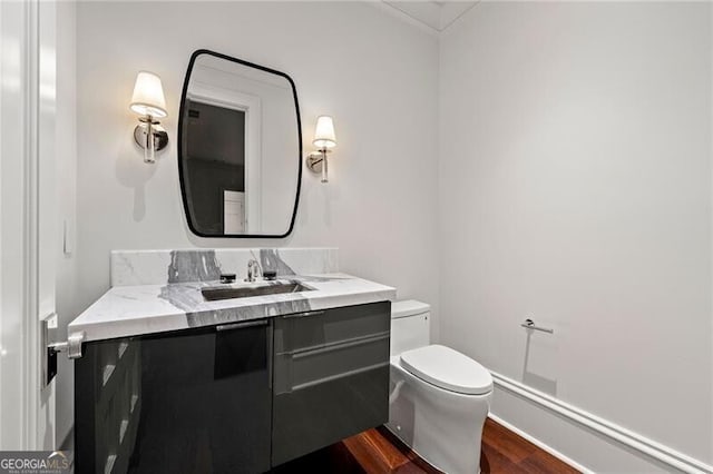 half bath with vanity, toilet, and wood finished floors