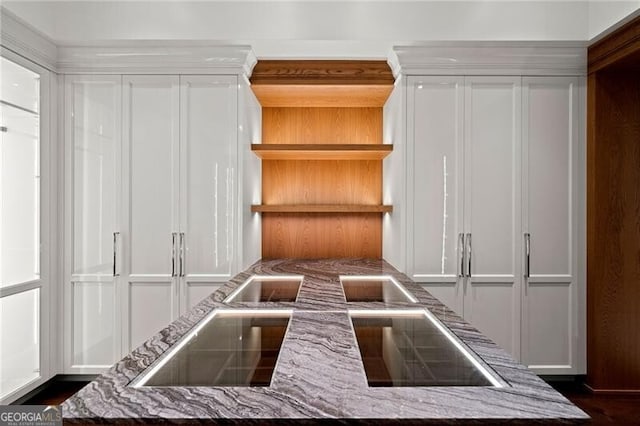 kitchen with open shelves, stone counters, and white cabinetry