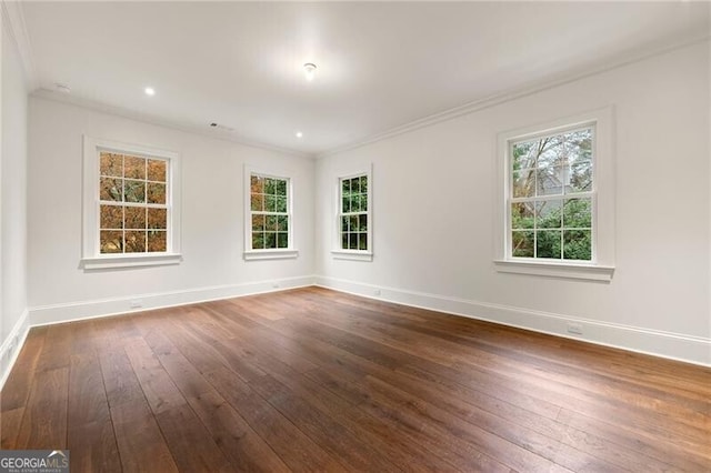 empty room featuring baseboards, a healthy amount of sunlight, crown molding, and dark wood-style floors