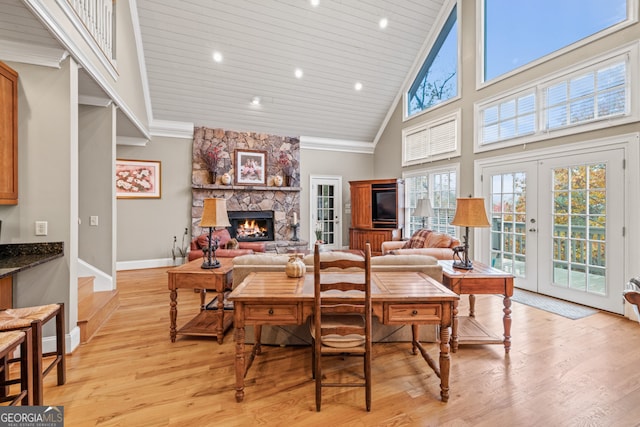 dining area featuring wooden ceiling, a stone fireplace, high vaulted ceiling, a notable chandelier, and light hardwood / wood-style floors