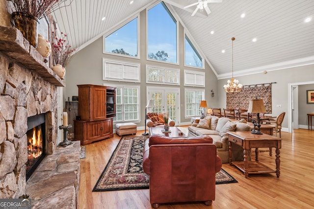 dining room with a stone fireplace, french doors, high vaulted ceiling, and light hardwood / wood-style flooring