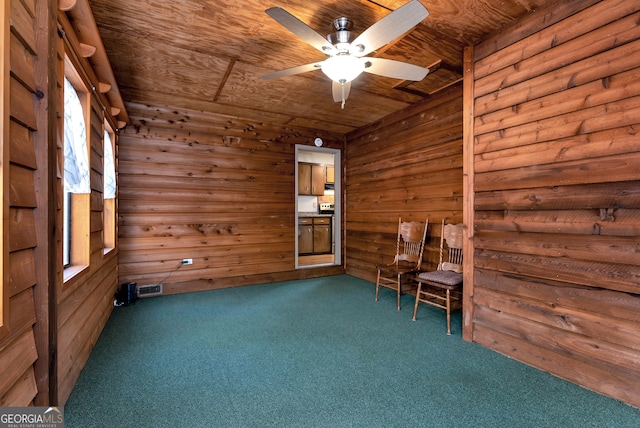 unfurnished room with ceiling fan, wooden walls, wooden ceiling, and dark carpet