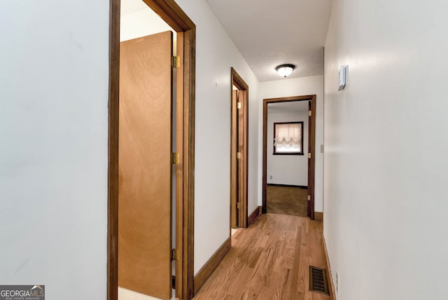 hallway featuring a textured ceiling and light hardwood / wood-style flooring