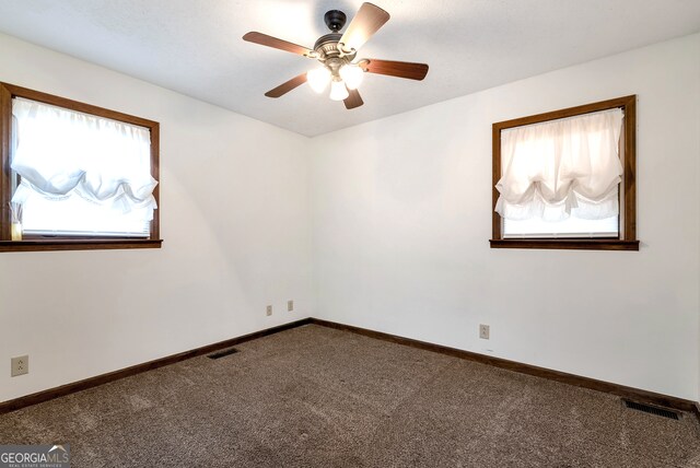 carpeted empty room with a wealth of natural light and ceiling fan