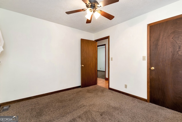 unfurnished room featuring ceiling fan, light colored carpet, and a textured ceiling