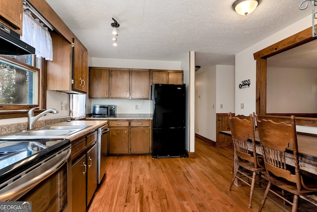 kitchen with a textured ceiling, light hardwood / wood-style floors, sink, and stainless steel appliances