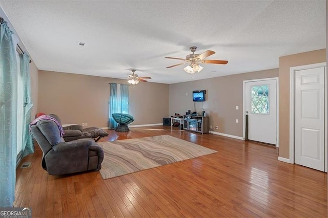 living room with hardwood / wood-style floors, ceiling fan, and a textured ceiling